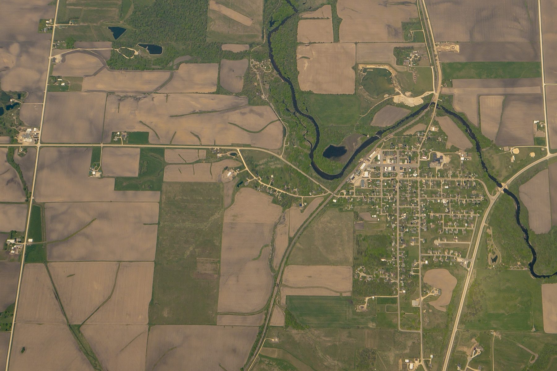 An Iowa town on a river bend, surrounded by fields, roads and timber
